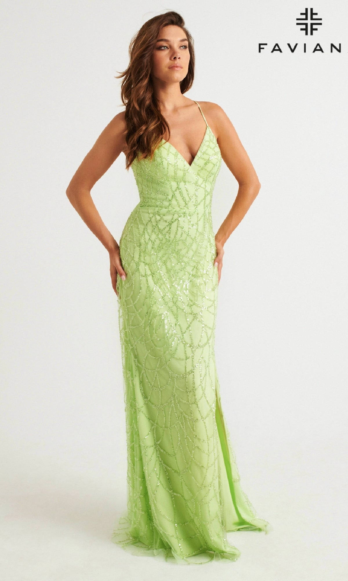 A woman wears the Glitter Faviana Long Strappy-Back Prom Dress 11084 in light green with thin straps and beaded details, standing against a plain white background. The Faviana logo appears in the top right corner.